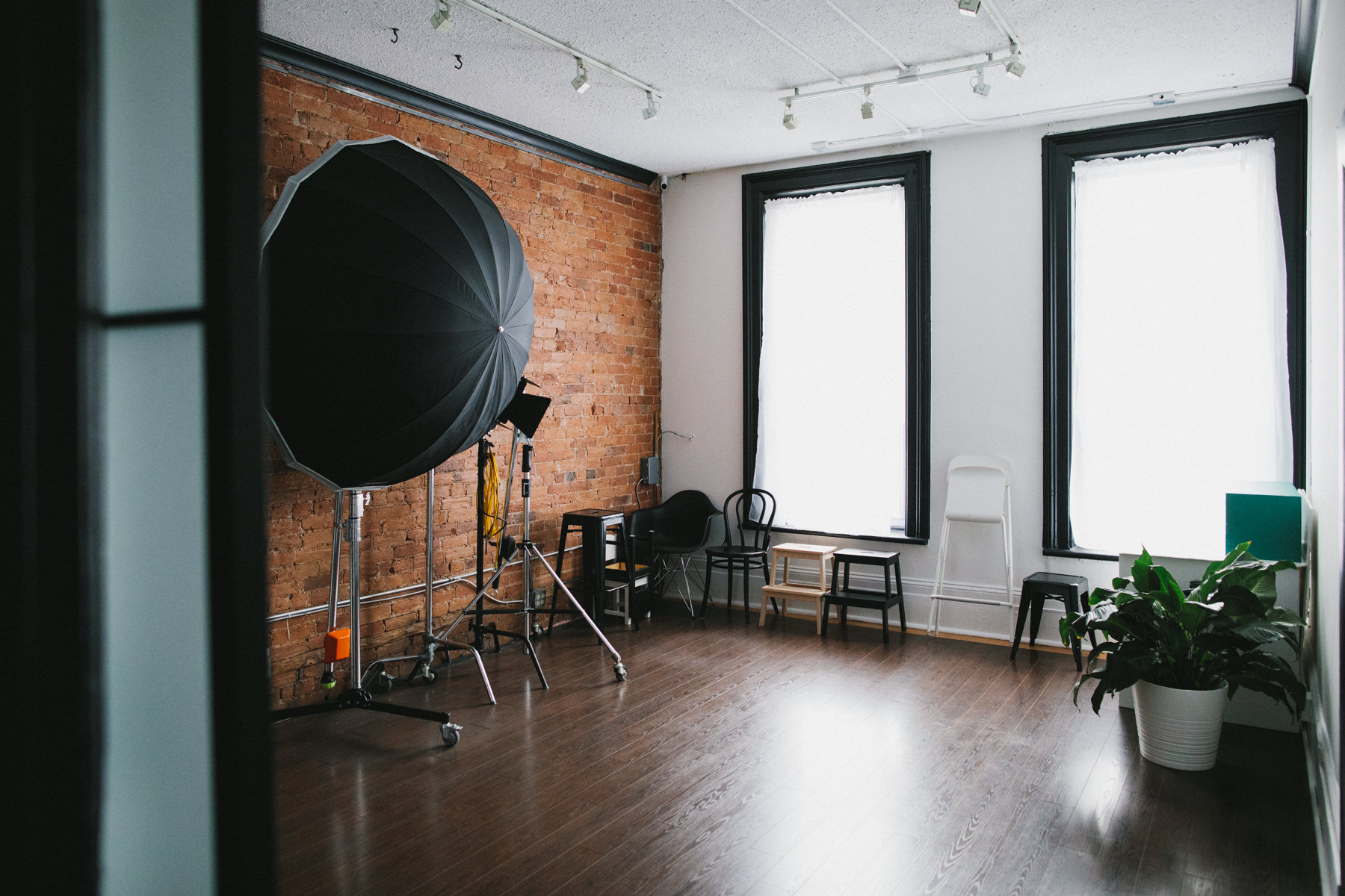 Photography studio with 2 large floor to ceiling windows, studio lights and lots of seating props.