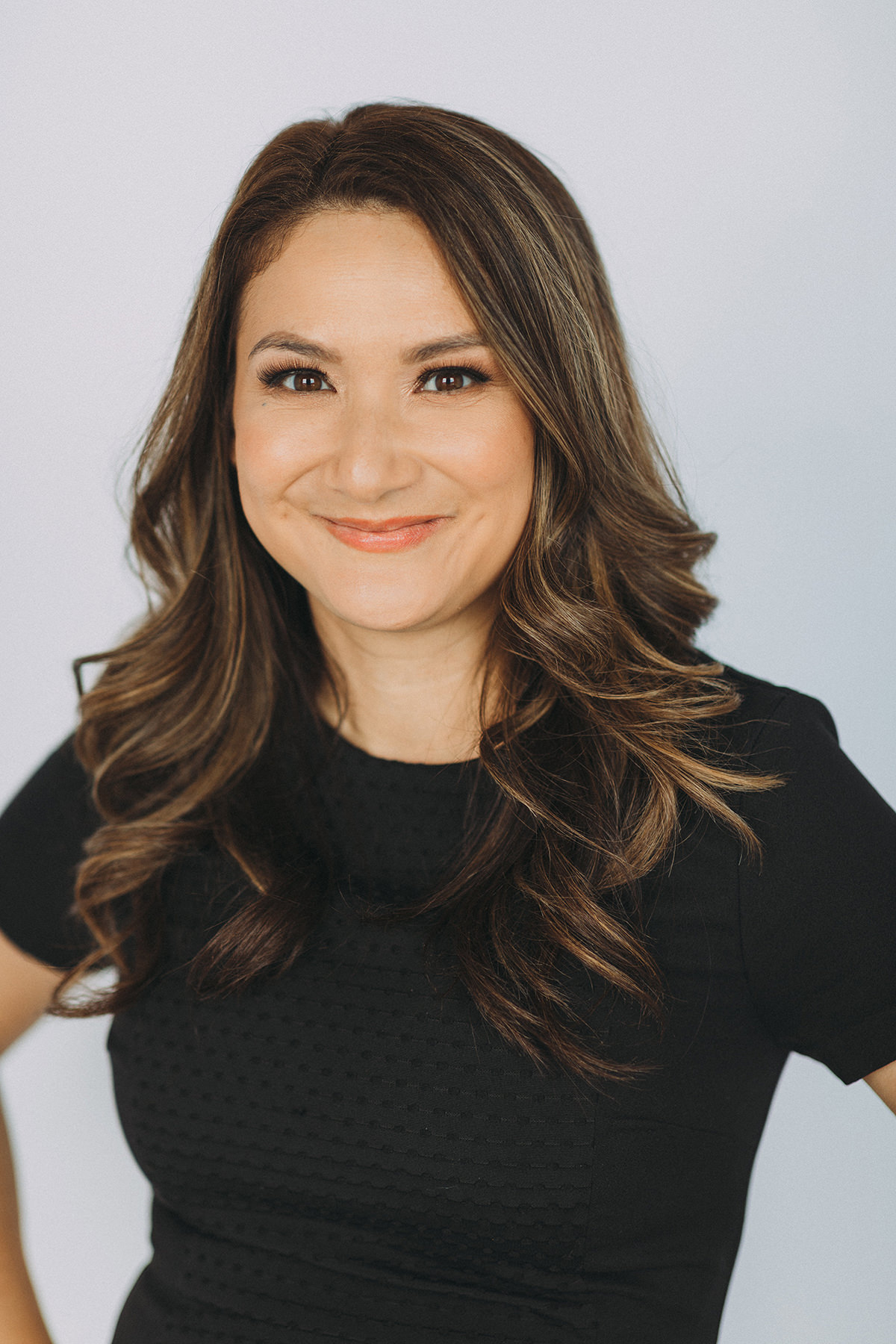 A headshot of a confident female lawyer in a black dress.