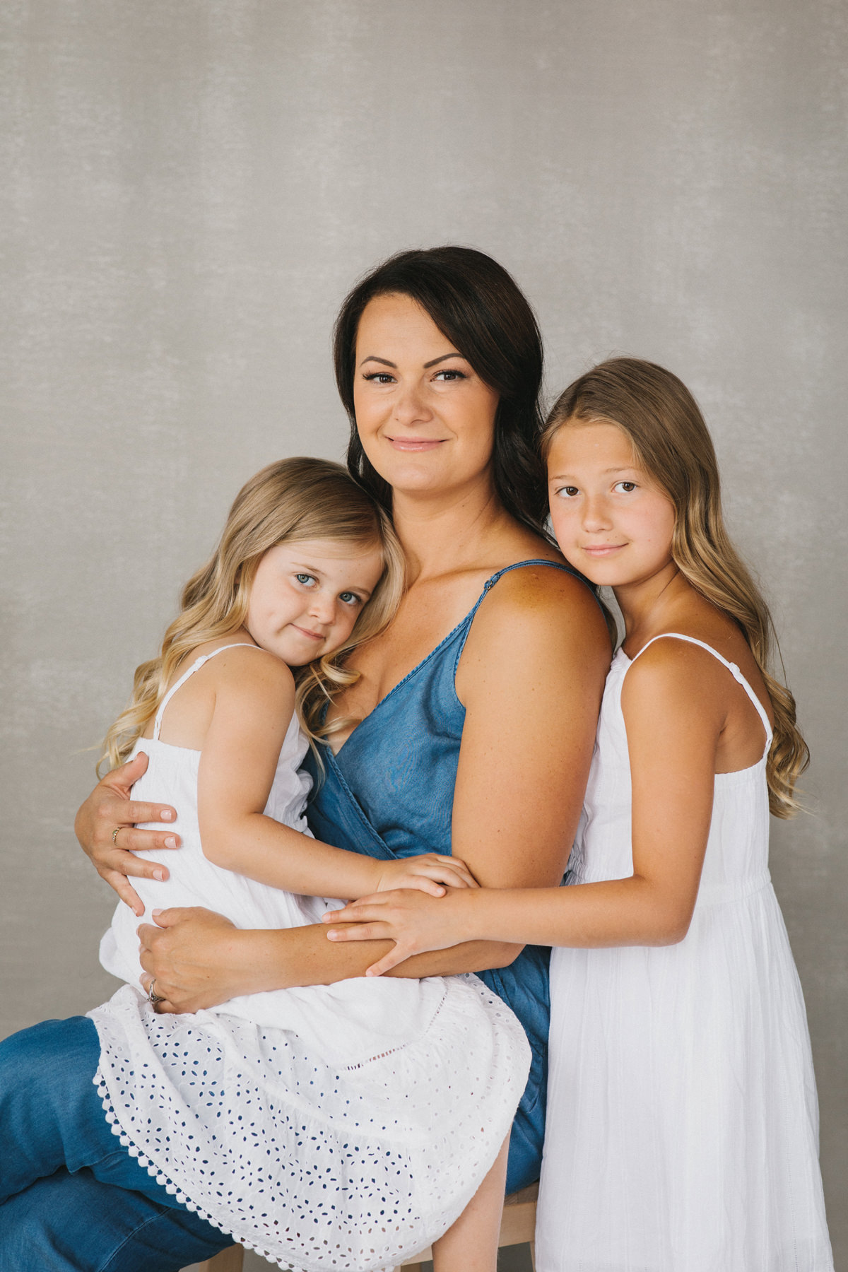 A portrait of a mother with her two young daughters. This was created in a photography studio.