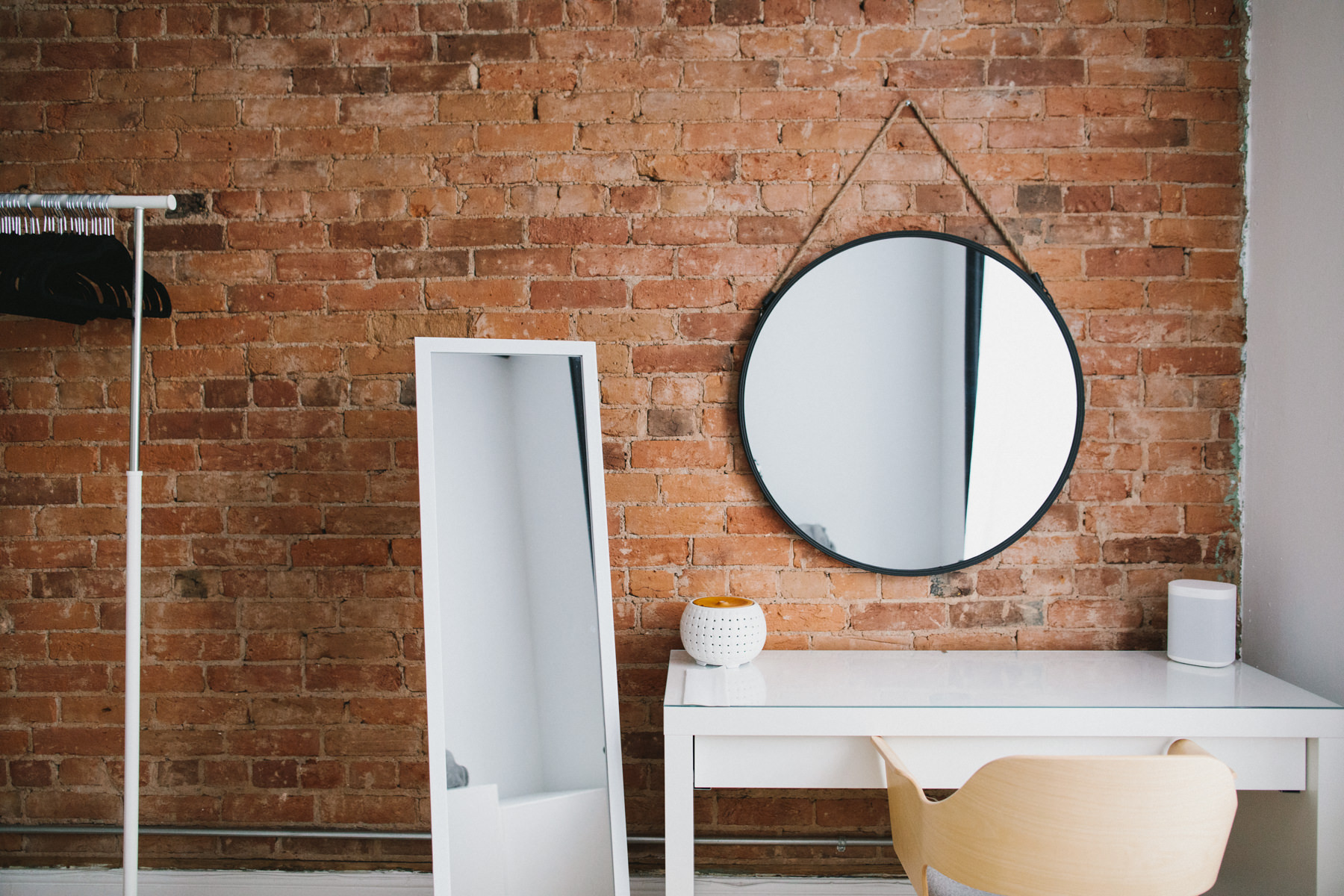 A beautiful area to have your hair and makeup done by a professional. It features a red brick wall, circle mirror hanging as well as a large floor standing full length mirror.