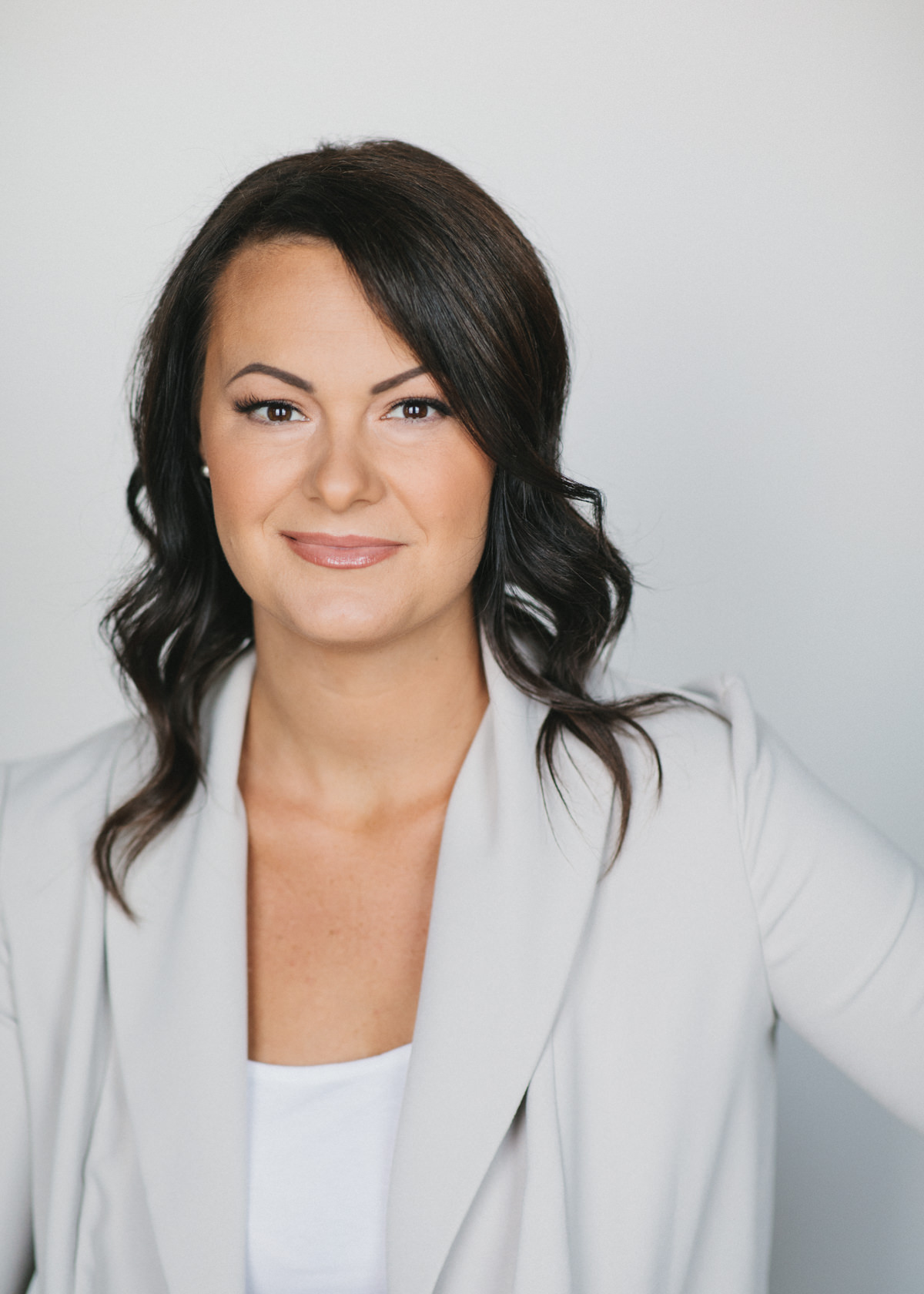 A professional headshot of a self employed woman wearing an off white blazer and white top.