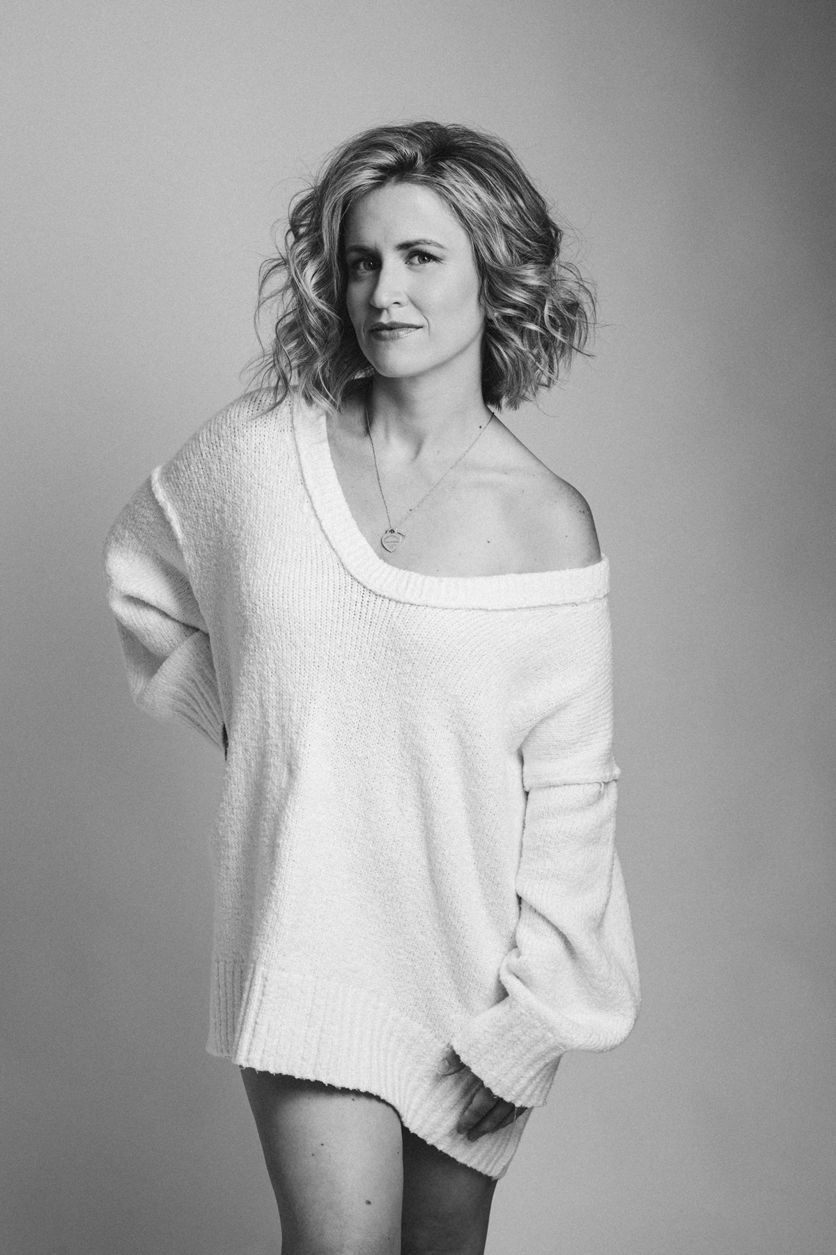 A black and white portrait of a woman wearing an oversized white sweater.