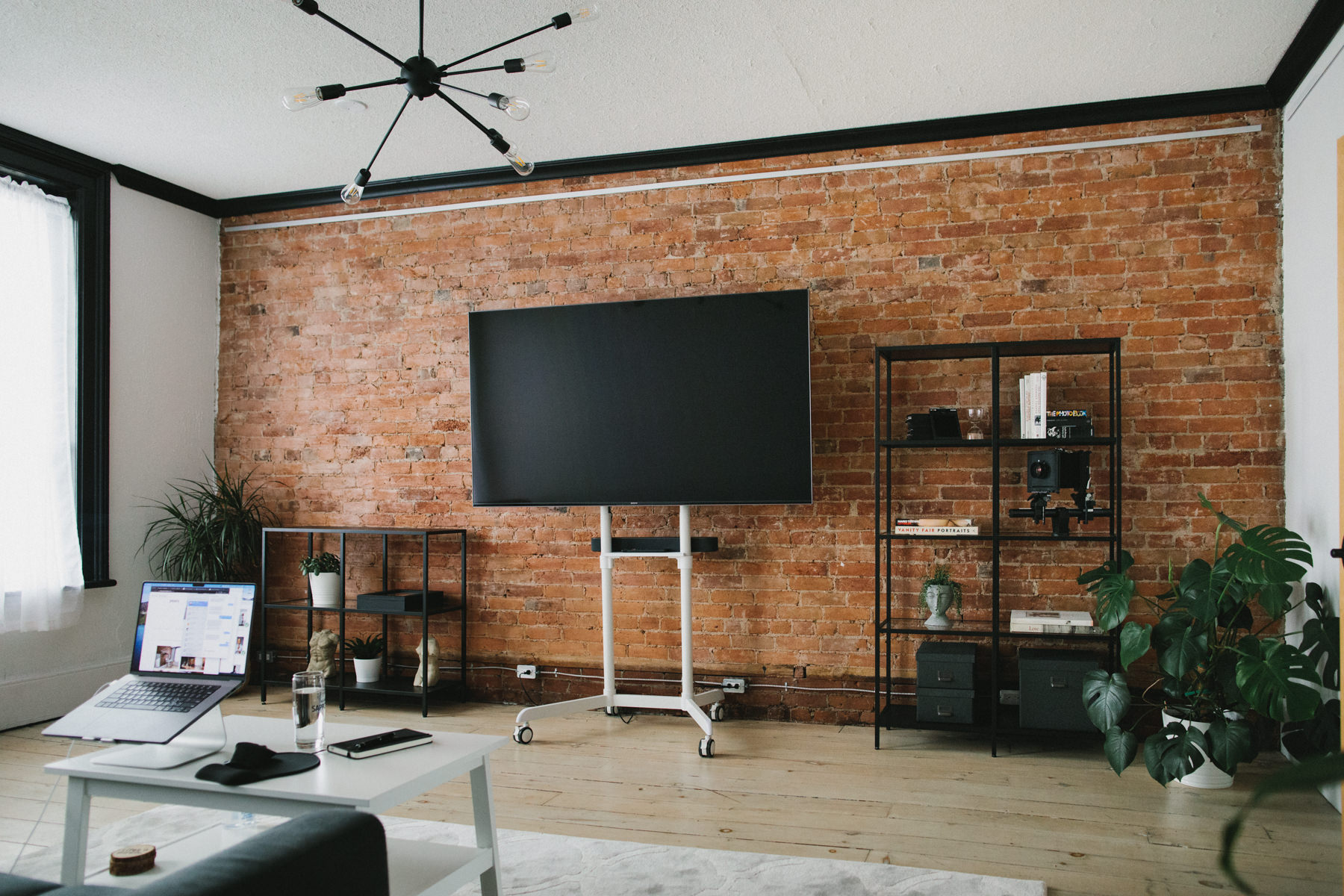 A room featuring a red brick wall and decorated with photography related decor.