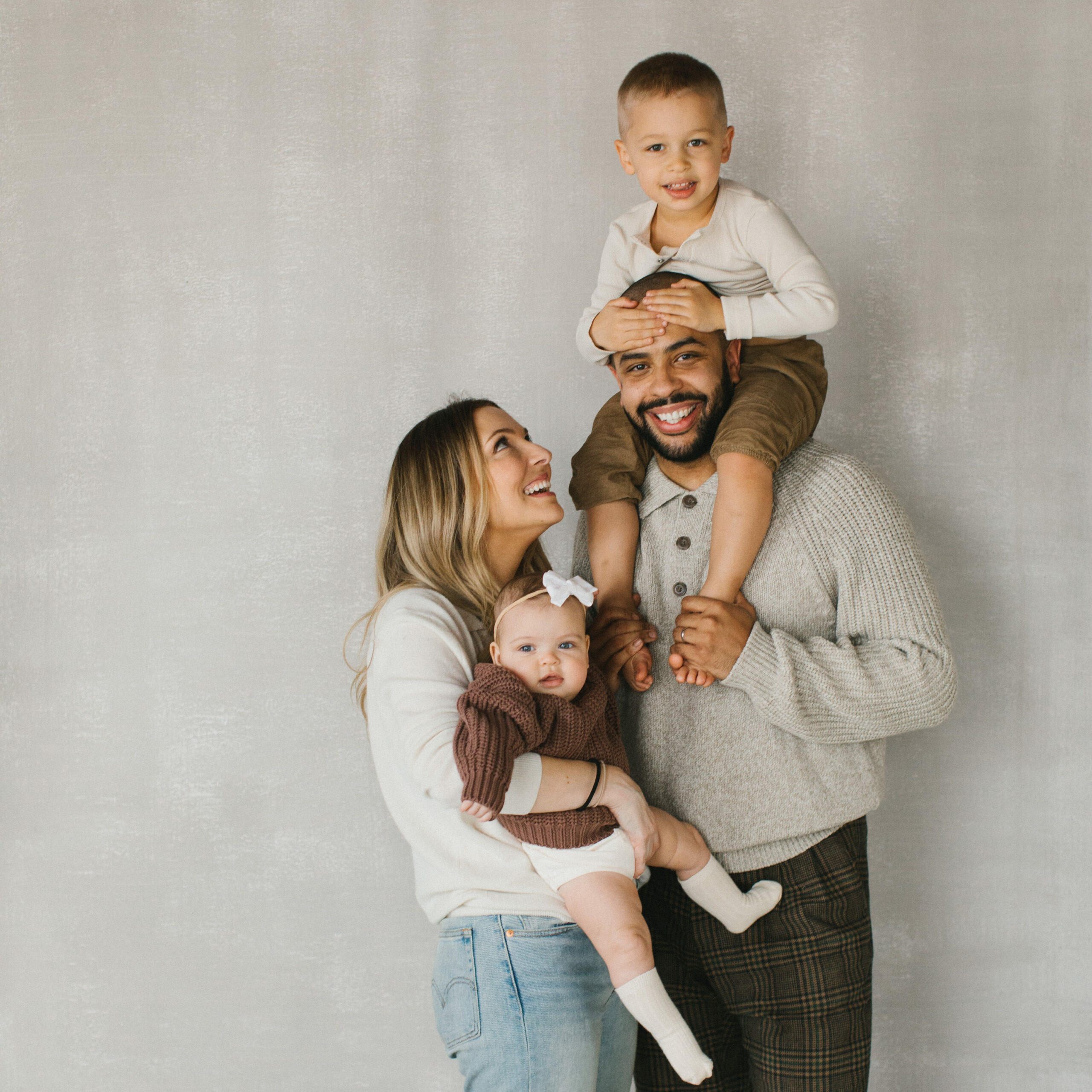 A portrait of a young family shot it a photography studio. The portrait features a mother, father, son and daughter.